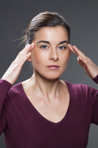 年轻女子按摩她的太阳穴皮肤光滑，头痛治疗图片下载