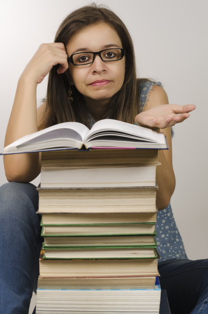 女人站在一堆书前。图片下载