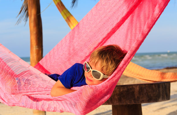 小男孩在沙滩上的吊床上休息图片下载