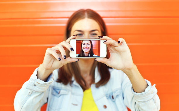 近距离女子在智能手机上自拍，查看屏幕图片下载