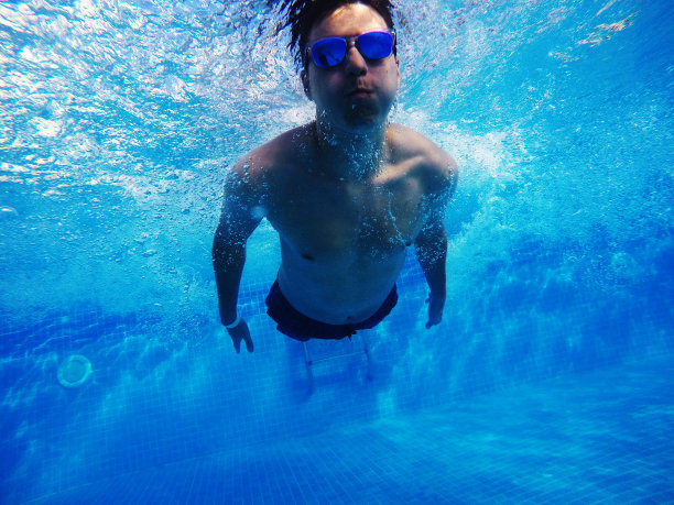 一个小男孩在游泳池里跳水图片下载