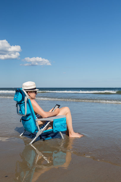 一个女人在海滩上看电子书图片下载