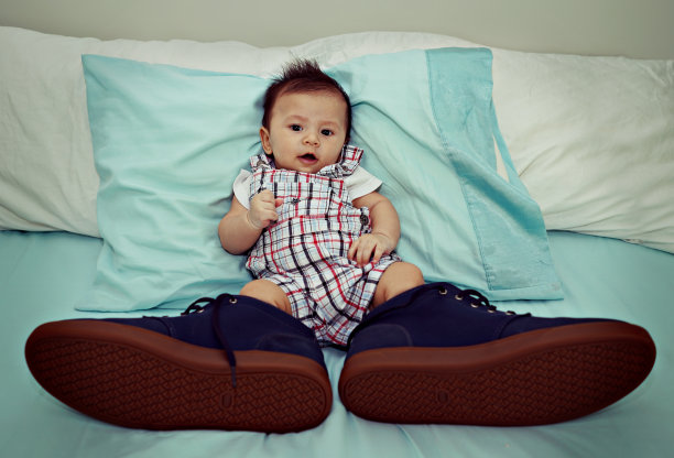亚洲宝宝在床上穿着大鞋子素材图片