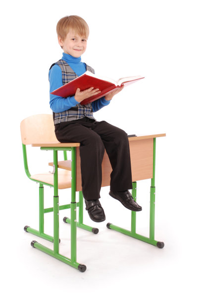 男孩坐在课桌上，拿着书图片下载