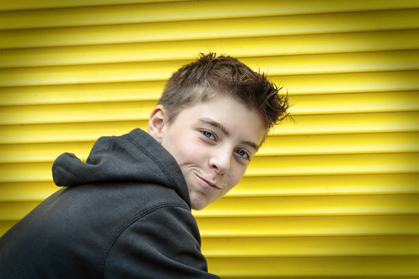 以黄色卷帘门为背景的少年图片下载