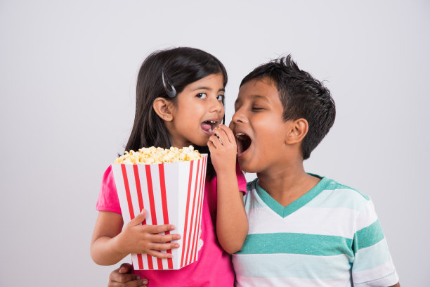 印度或亚洲可爱的女孩和男孩吃爆米花图片下载