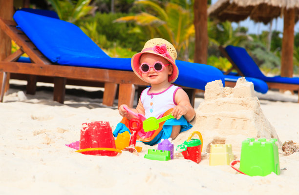 可爱的小女孩在海滩上建造沙堡图片下载