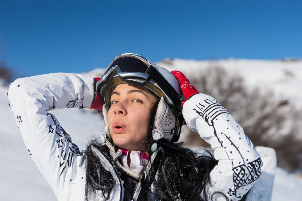 在晴天戴头盔和护目镜的女滑雪者图片下载