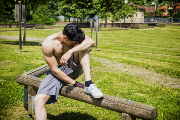 赤膊运动的年轻人在城市公园休息，坐着图片下载