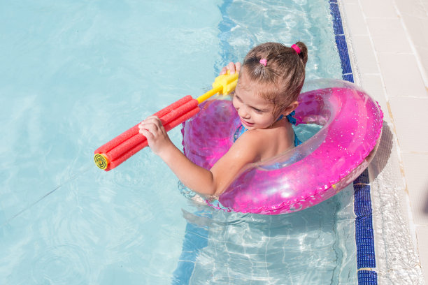 小女孩在游泳池里玩水枪。图片下载