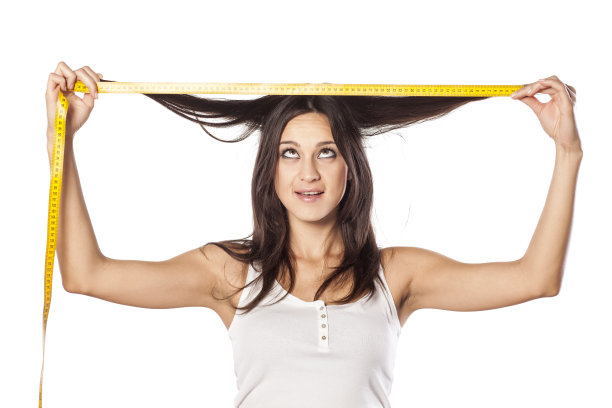 有趣迷人的女孩用卷尺量她的头发图片下载