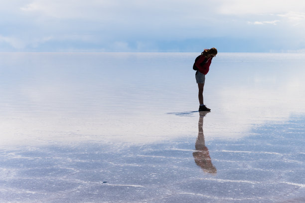 女孩站在乌尤尼潮湿的盐滩上图片下载