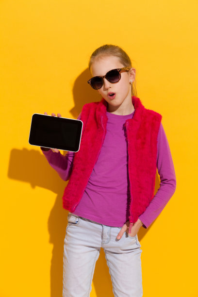 一个小女孩正在展示一个数码平板电脑。图片下载