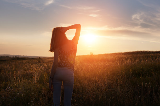 自由快乐的年轻女子举起手臂在日落图片下载