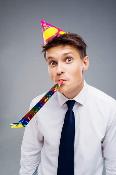 年轻的办公室经理戴着派对帽和吹风机图片下载