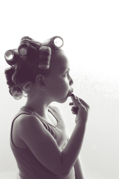 小女孩戴着卷发器在涂口红图片下载