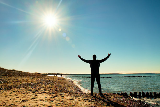 穿西装的高个子在防波堤的石头海滩上锻炼。图片下载