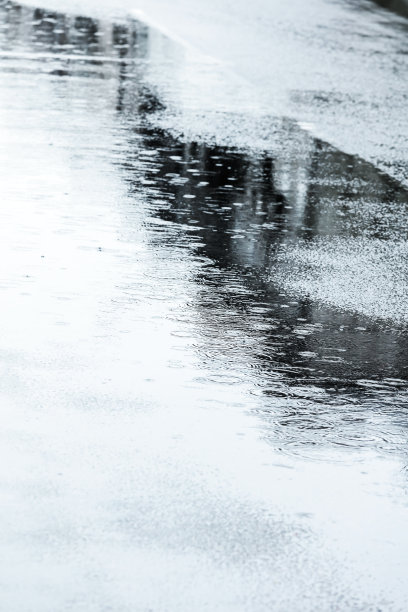 下雨时，潮湿的街道人行道上有雨滴和水坑图片下载