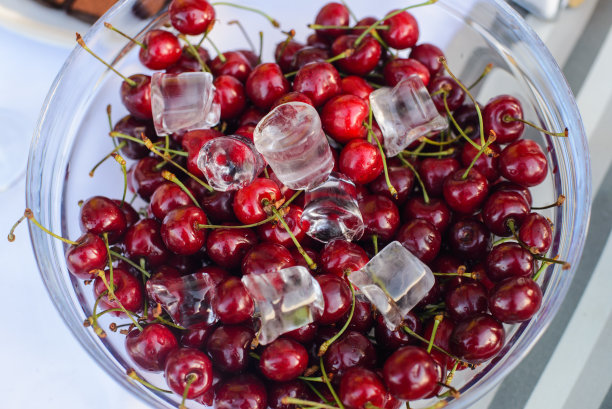 新鲜的冷樱桃放在玻璃碗里放在桌上图片下载