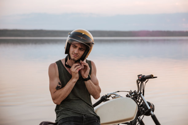 一名男子坐在摩托车上试图摘下头盔图片下载