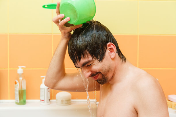 年轻的微笑的男人在浴室里洗着水床单图片下载