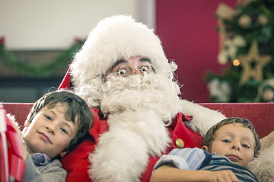 圣诞老人坐在两兄弟之间的沙发上图片下载