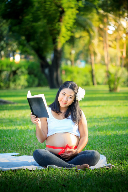 美丽的亚洲孕妇在公园看书图片下载
