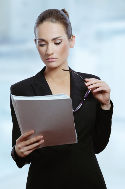 年轻迷人的女商人手里拿着眼镜阅读合同图片下载