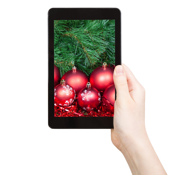 手持带有红色圣诞装饰品的平板电脑图片下载