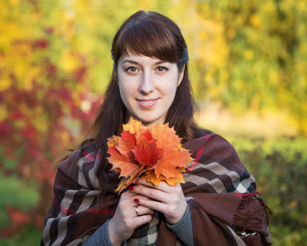 美丽的女孩手拿枫叶在大自然的背景上图片下载