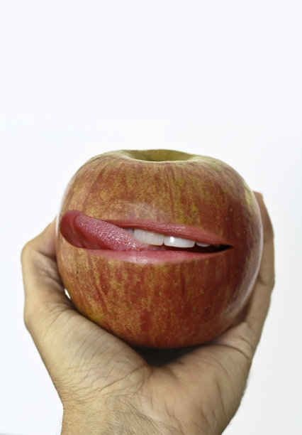 手捧着一个舔着嘴唇的苹果图片下载
