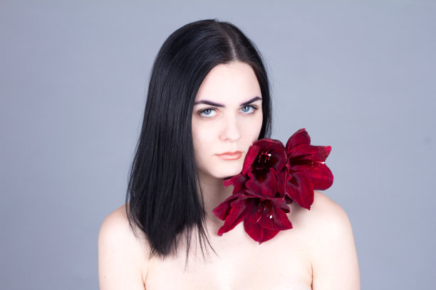 一头漂亮的黑发，肩上有朵花。美容治疗。图片下载