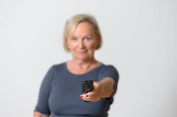 成年妇女拿着遥控器对抗灰色图片下载