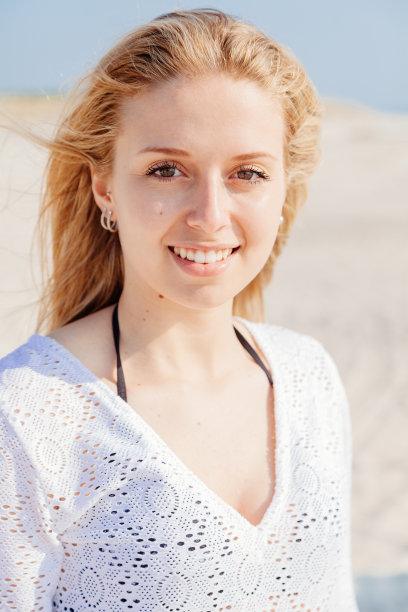 一个微笑的女人在日落的海滩上的肖像图片下载