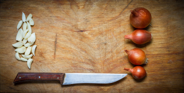 洋葱，大蒜和刀放在质朴的木桌上。图片下载