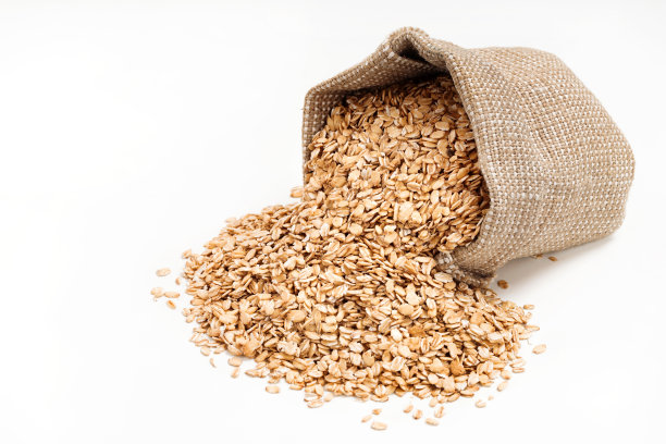 燕麦片从袋子里散落在白色的背景上。图片下载
