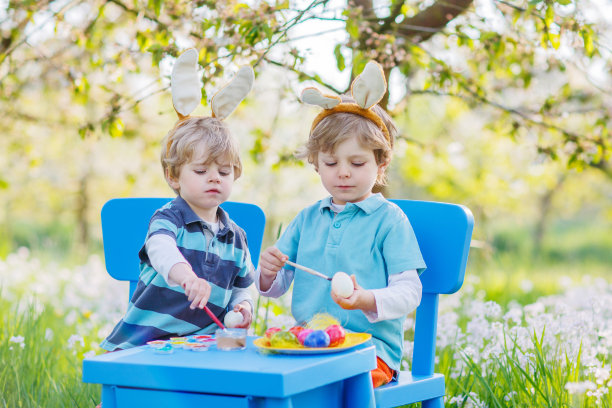 两个小朋友在复活节兔子的耳朵里给鸡蛋上色图片下载