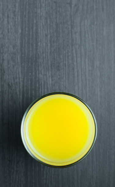 木背景上的玻璃杯里的橙汁。图片下载