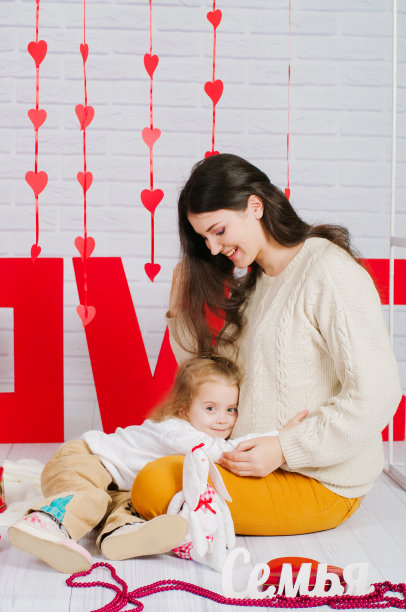 年轻的妈妈和她的宝贝女儿一起装饰情人节图片下载