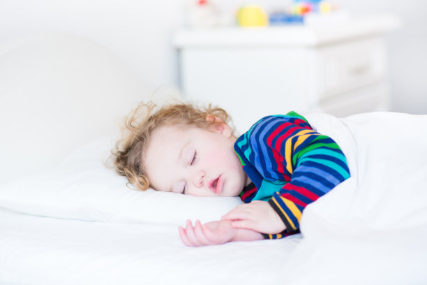 可爱的幼儿女孩在阳光明媚的白色卧室里小睡素材图片