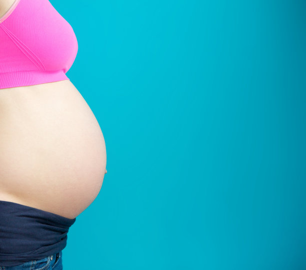 侧视图近孕妇的肚子上的蓝色背景图片下载