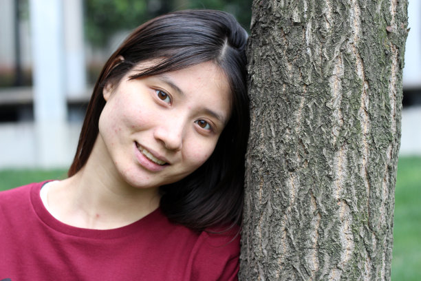 快乐的中国女孩倚在树上图片下载