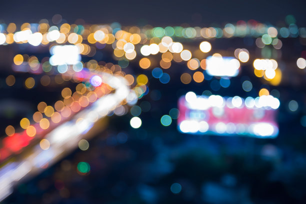 夜色模糊了城市道路的弯曲，抽象的散景灯光背景图片下载