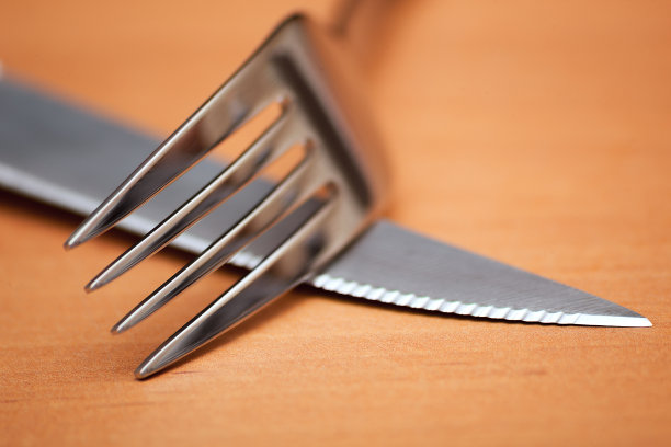 一个银色的刀，叉子在一个棕色的桌子上的特写图片下载