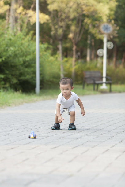可爱的小男孩在公园里玩玩具车图片下载