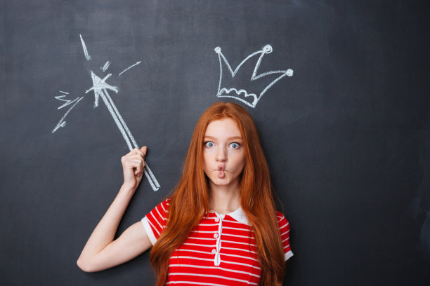 滑稽的女人戴着皇冠，用魔杖在黑板上画着图片下载