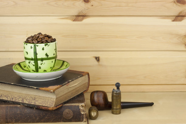 马克杯咖啡豆和旧书在书架上。图片下载