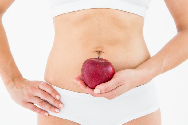 身材苗条的女人把苹果放在肚子前图片下载