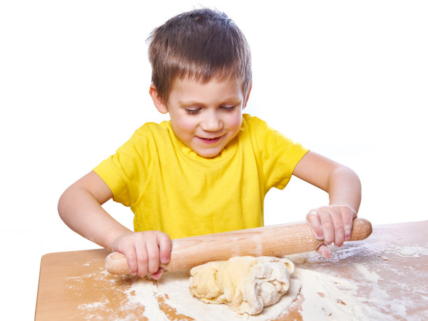 快乐的小男孩在厨房的桌子上揉面团图片下载