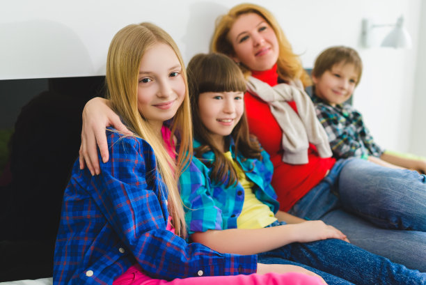 母亲抱着孩子坐在室内的床上。幸福的家庭图片下载